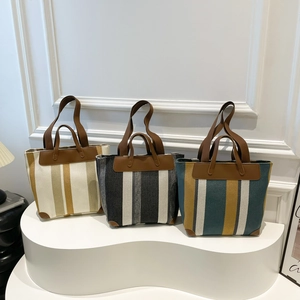 Trois sacs cabas tissés à rayures avec garniture en cuir sur un support minimaliste