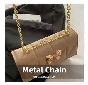 Close-up of golden metal bow hardware and chain strap on apricot quilted handbag