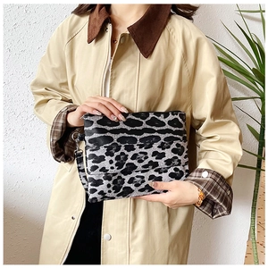 Close-up of leopard print clutch bag featuring textured fabric and detachable metal hook