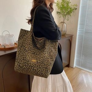 Detailed view of leopard print canvas tote bag with a handmade metal tag on the side