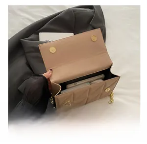 Macro detail of beige quilted handbag showing dual gold magnetic clasps and internal space