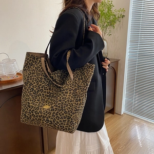 Detail of the leopard print canvas tote bag featuring an oval Handmade logo plaque