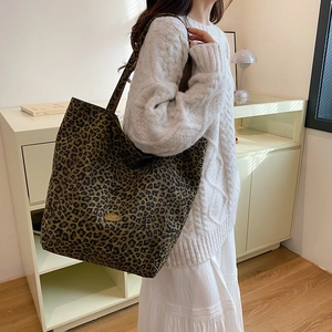 Detailed close-up of leopard print canvas tote bag with handmade metal plaque detail