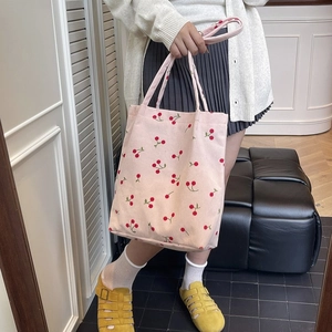 Dettaglio della borsa tote in velluto a coste rosa con ciliegie e doppi manici