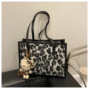 Gros plan du sac cabas en fausse fourrure léopard avec lanières en cuir et breloque chat