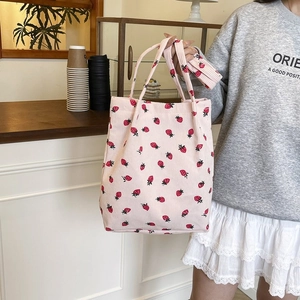 Dettaglio della borsa tote in velluto rosa con stampa a fragola e trama della tracolla