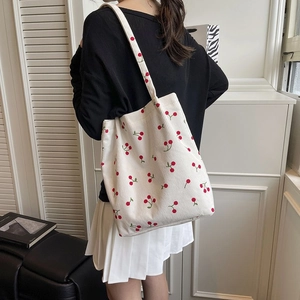 Dettaglio della borsa tote in velluto a coste bianco con ricami di ciliegie rosse e texture
