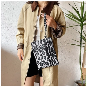 Close-up of leopard print wristlet bag with metal zipper held by model in trench coat