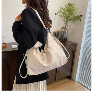 Detail of off-white oversized shoulder bag featuring drawstring texture and plush cloud charm