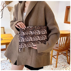 Detail of leopard print clutch bag with wrist strap in a cozy cafe setting