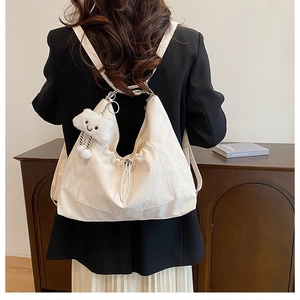 Detail view of cream white pleated backpack with a cute cloud plush pendant accessory