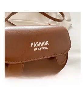 Detail of a brown PU leather crossbody bag with cute ear accents and texture
