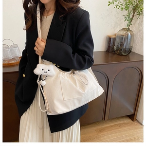 Detail of white nylon tote bag featuring drawstring pleats and cloud plush charm