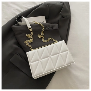 Detail view of quilted white shoulder bag with gold chain strap and diamond stitching