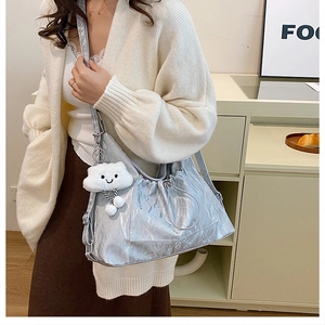 Silver-grey tote bag with pleated metallic texture and a smiling plush cloud pendant