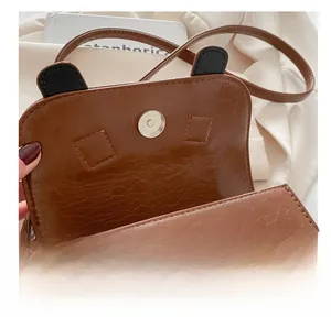 Close-up of brown vintage crossbody bag featuring a durable gold magnetic buckle closure