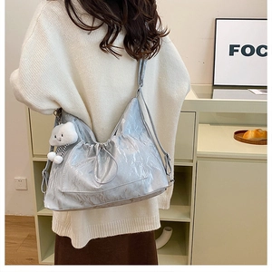 Detail of light blue wrinkled shiny tote bag with a cute white cloud plush pendant