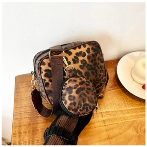 Detail of leopard print crossbody bag set featuring a wide strap and small round coin purse