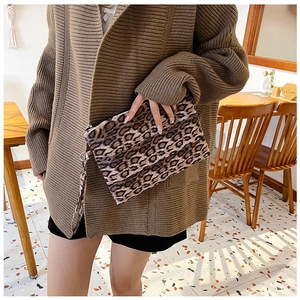 Detail of leopard print wristlet bag with zipper closure held in a cozy cafe setting