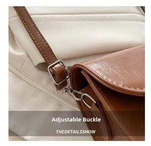 Close-up of silver metal buckle and vintage brown cracked leather texture on a crossbody bag