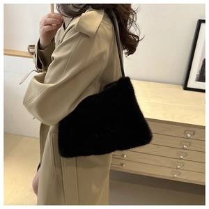 Detailaufnahme der schwarzen Plüsch-Schultertasche auf khakifarbenem Trenchcoat