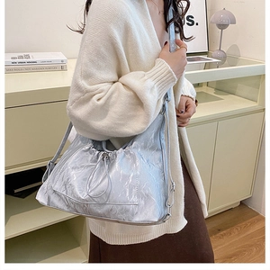 Detail of silver-blue hobo bag with pleated metallic texture and chain strap on model