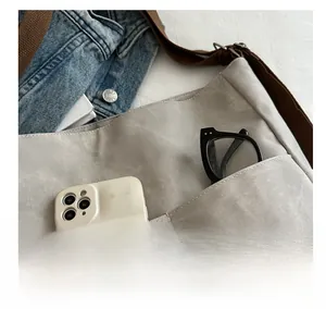 Detail view of the front storage pocket on light grey canvas bag with smartphone and glasses