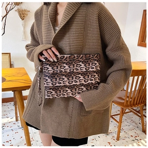 Detail of leopard print clutch with wrist strap shown in a cozy indoor cafe setting