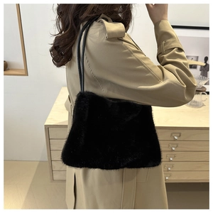 Detailansicht einer schwarzen Plüsch-Tasche mit Lederriemen zum beigen Trenchcoat