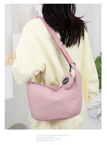 Detail of pink corduroy crossbody bag with heart-shaped coin pouch and fashion logo strap