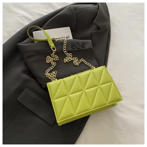 Detailed macro view of lime green quilted handbag with golden chain strap and PU leather texture