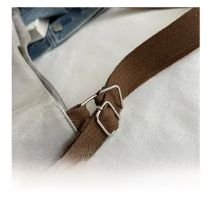 Close-up of adjustable metal buckle on brown woven strap of a canvas backpack