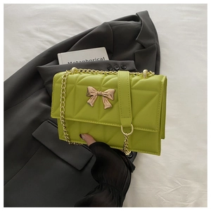 Detail of avocado green quilted leather bag featuring a gold bow clasp and chain strap