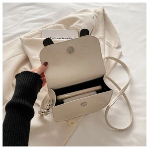 Close-up of cream small square crossbody bag showing internal space and magnetic closure