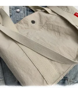 Detail of durable nylon tote bag featuring thick woven straps and a unique pleated design
