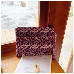 Close-up of leopard print wristlet bag in pink and black on a wooden ledge