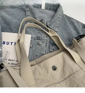 Close-up of khaki nylon tote bag with metal logo on denim jacket background