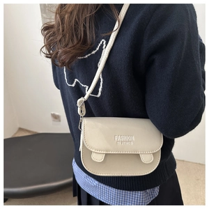 Close-up of beige leather crossbody bag with half-round flap and fashion slogan
