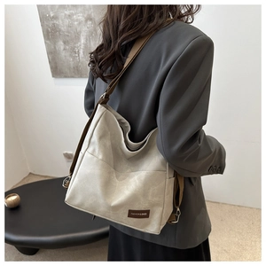 Detailed back view of a minimalist beige crossbody bag with fashion label and brown strap