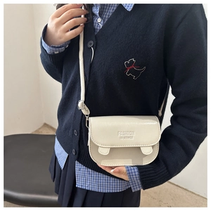 Detail of minimalist cream-white crossbody bag with fashion inscription on textured leather