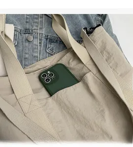 Detail view of large side pocket on apricot nylon tote bag showing space for a smartphone