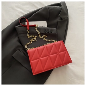 Detail of red quilted triangle pattern on matte leather bag with metal chain strap