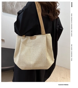 Dettaglio della borsa tote intrecciata con spalline in pelle marrone e logo applicato
