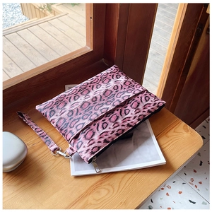 Pink leopard print clutch bag with fabric texture and silver zipper on a magazine