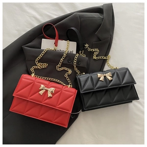 Detailed close-up of quilted crossbody bags with golden bow clasp and metal chain straps