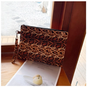 Detail shot of leopard print clutch featuring a black zipper and detachable wrist strap