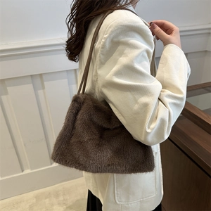 Dunkelbraune Shopper-Tasche aus Kunstpelz mit Lederriemen getragen im winterlichen Stil