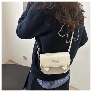 Detail of a creamy white mini crossbody bag with fashion inscription on a stylish outfit
