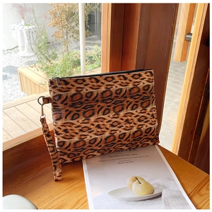Detail of leopard print faux leather clutch bag with metal zipper on wooden table