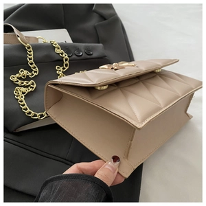 Detail view of beige quilted chain bag with gold butterfly clasp and metallic strap
